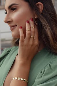 Close-up of an elegant woman in a green blouse showcasing gold jewelry.