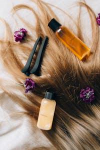 Aesthetic flatlay of hair care items and flowers against a soft background.