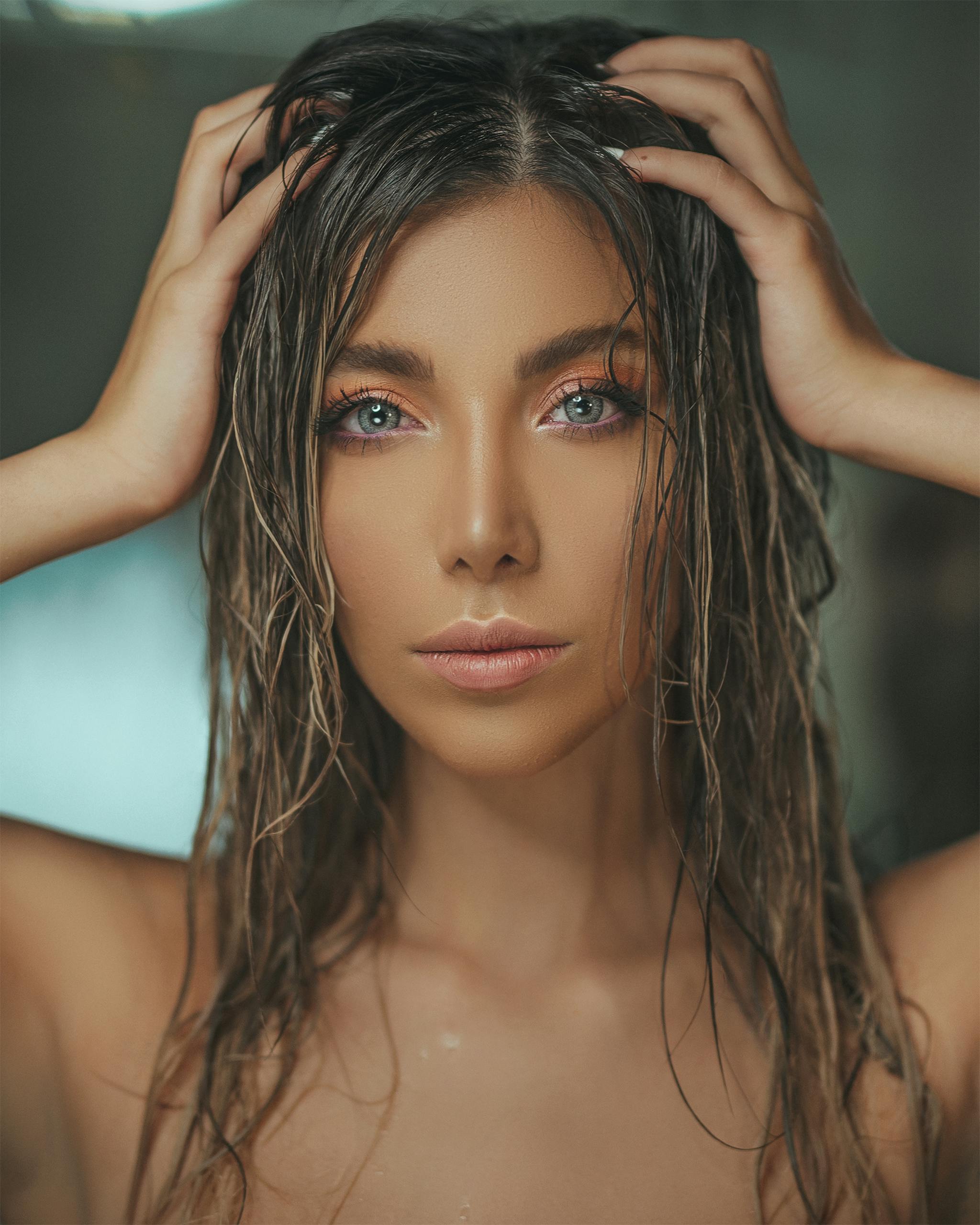 A stunning portrait featuring a woman with eye-catching makeup and wet hair, captured in a close-up shot.