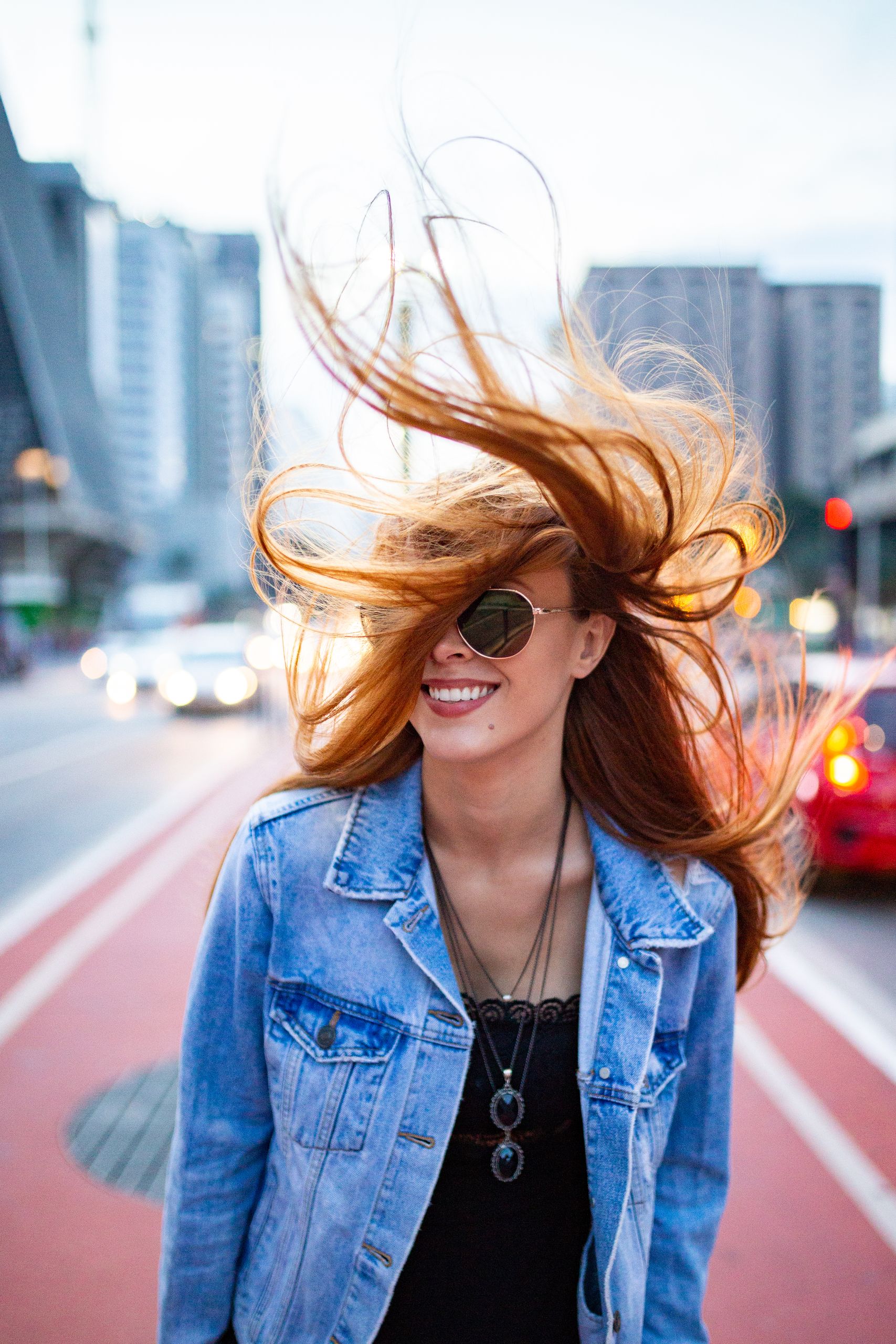 Vibrant street portrait of a smiling woman with flowing hair in São Paulo, Brazil.
