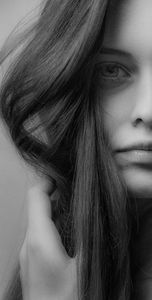 Striking black and white portrait of a woman showcasing her expressive eye and flowing hair.